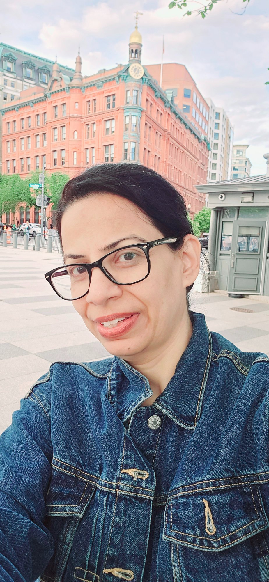 Head-and-shoulders portrait of Syeda Jaana Ali, dark hair tied back, wearing a denim jacket and glasses.
