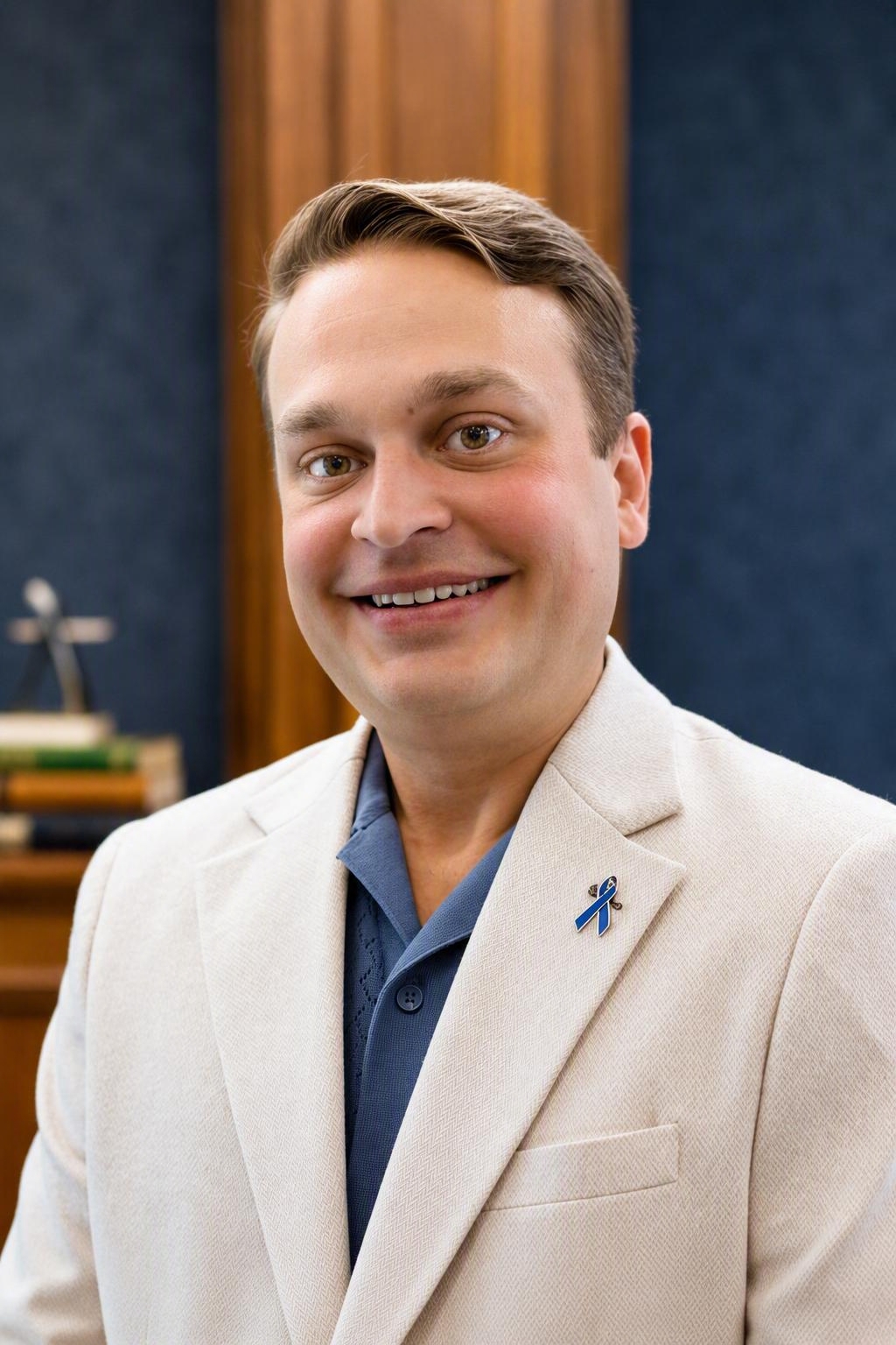 Head-and-shoulders portrait of Christopher Mammoliti, short brown hair, wearing a cream blazer and blue shirt.
