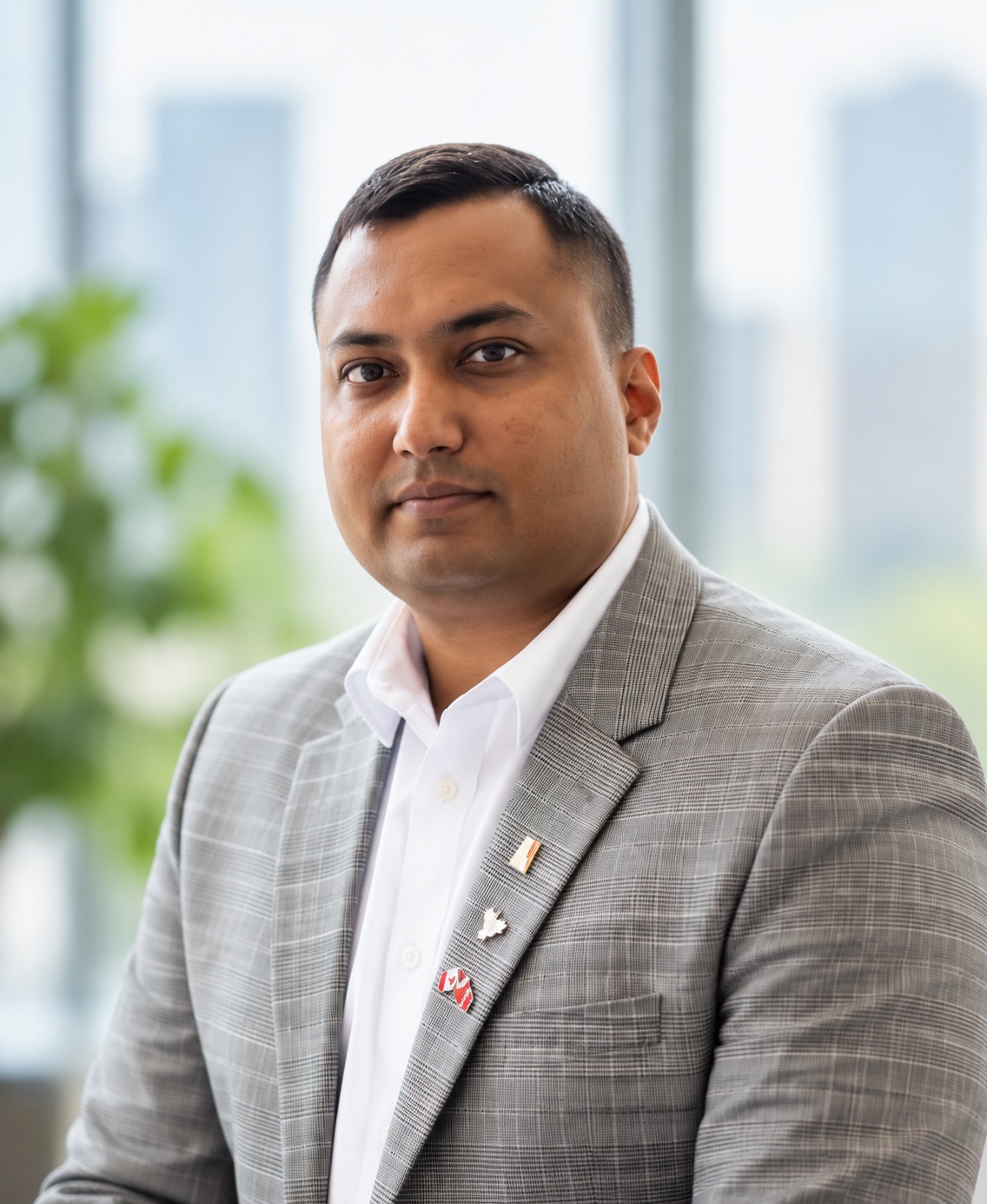 Head-and-shoulders portrait of Ashan Fernando, short dark hair, wearing a grey plaid jacket.