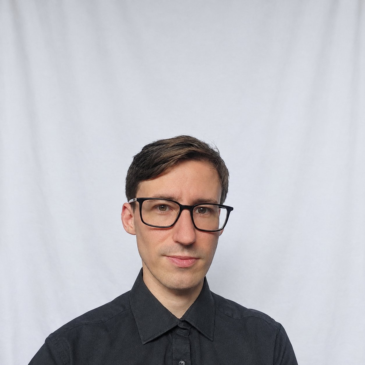 Head-and-shoulders portrait of Paul Viret, short brown hair, wearing black-framed glasses and a dark shirt.