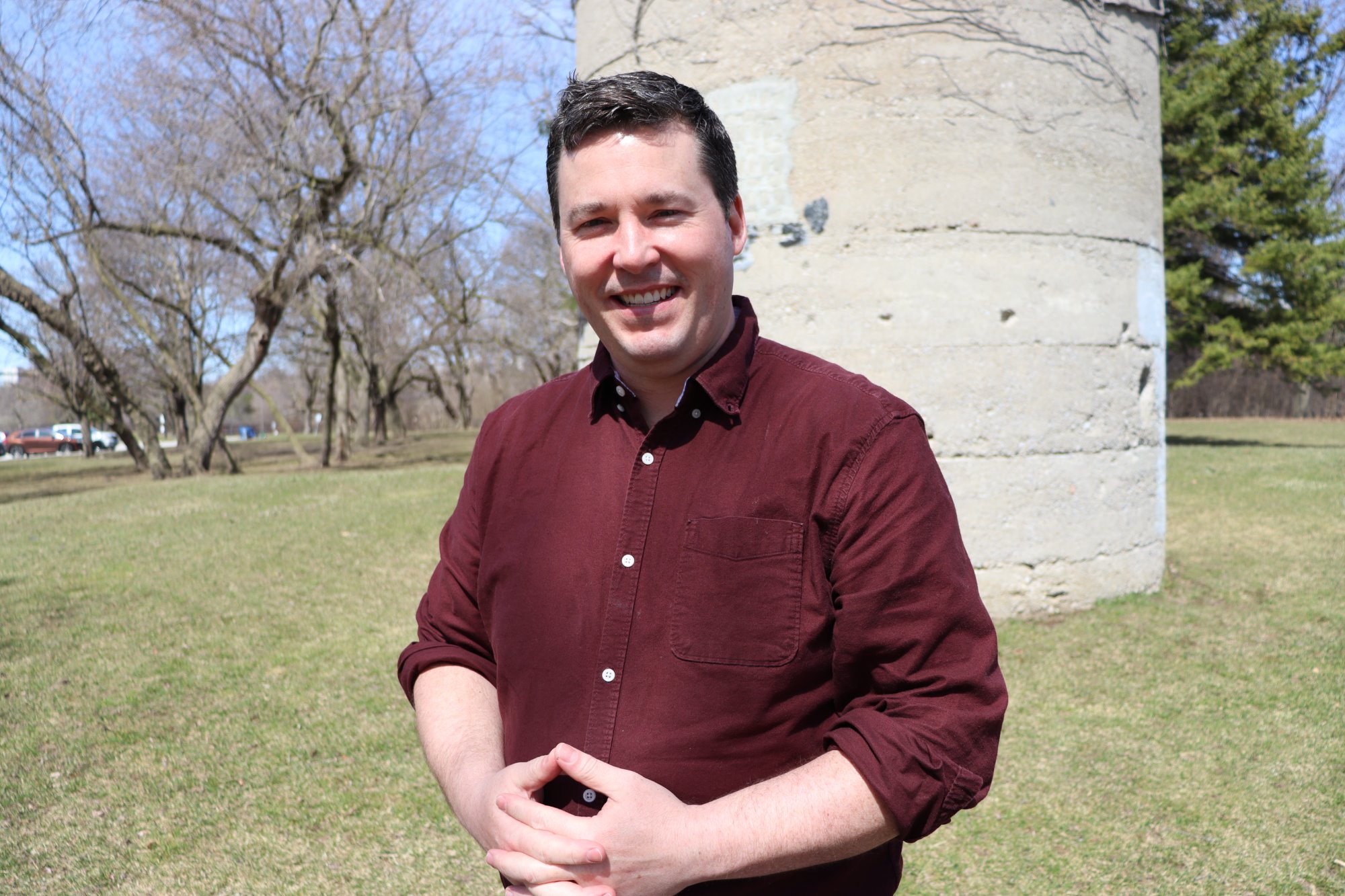 Head-and-shoulders portrait of Dan Lovell, short dark hair, wearing a maroon shirt.