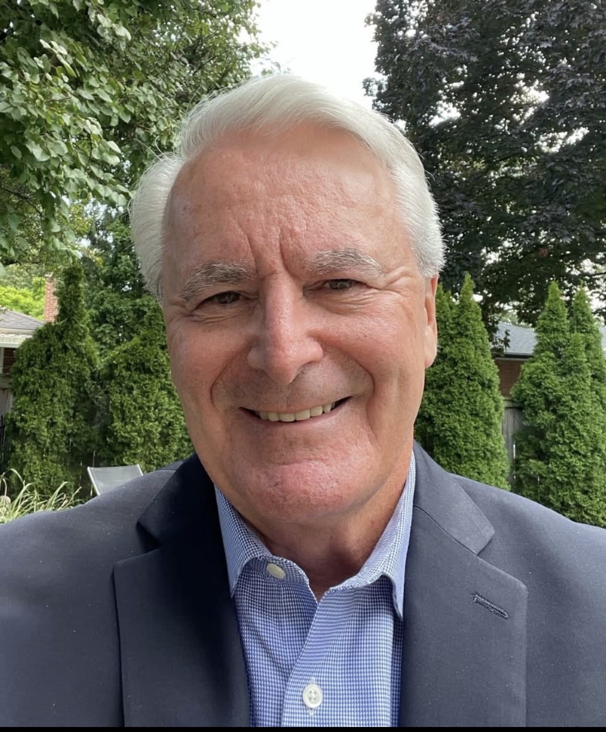 Head-and-shoulders portrait of Markus de Domenico, short white hair, wearing a navy blazer and checked shirt.