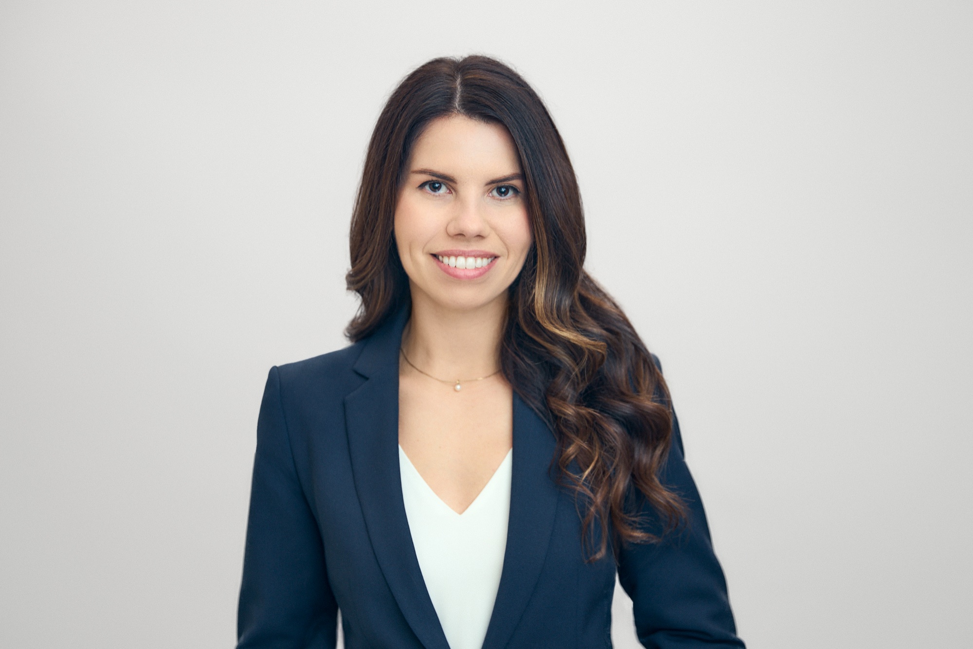 Head-and-shoulders portrait of Jocelyne Poirier, long wavy brown hair, wearing a navy blazer and white top.