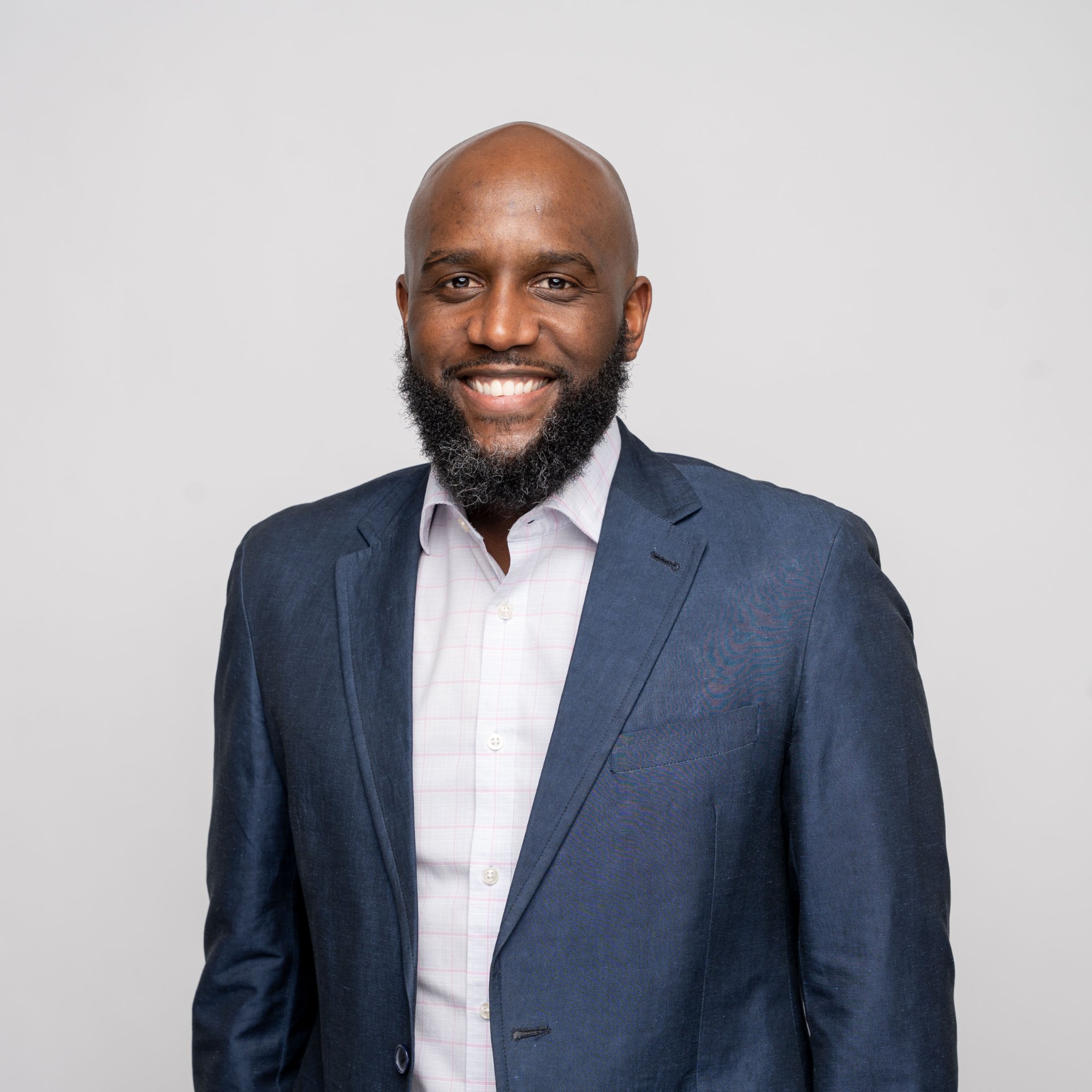Head-and-shoulders portrait of Jeffery Adamson, a beard, wearing a navy blazer and checked shirt.