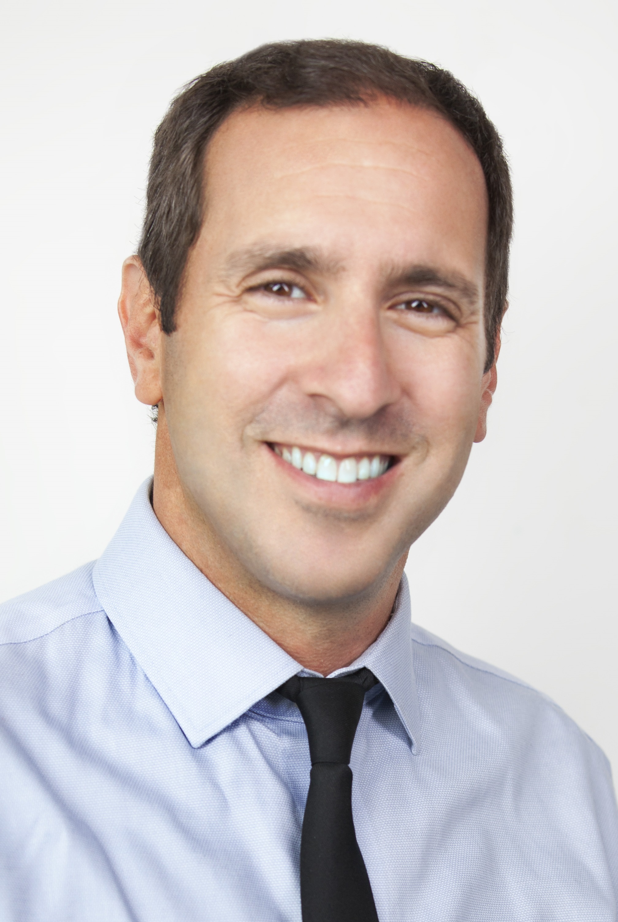 Head-and-shoulders portrait of Josh Matlow, short dark hair, wearing a light blue shirt and black tie.