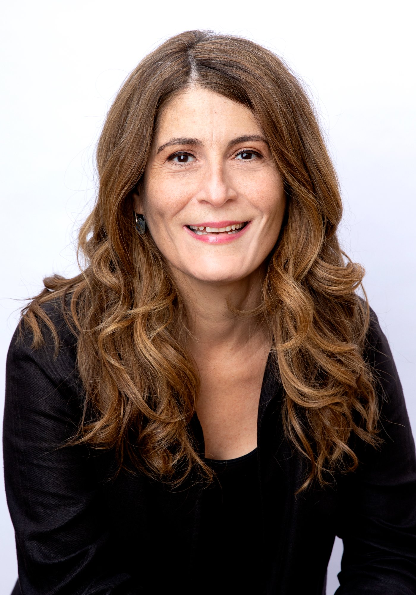 Head-and-shoulders portrait of Mary Fragedakis, long wavy brown hair, wearing a black top.