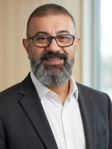 Head-and-shoulders portrait of Mohammad Shabani, short grey hair and a grey beard, wearing glasses and a dark blazer.