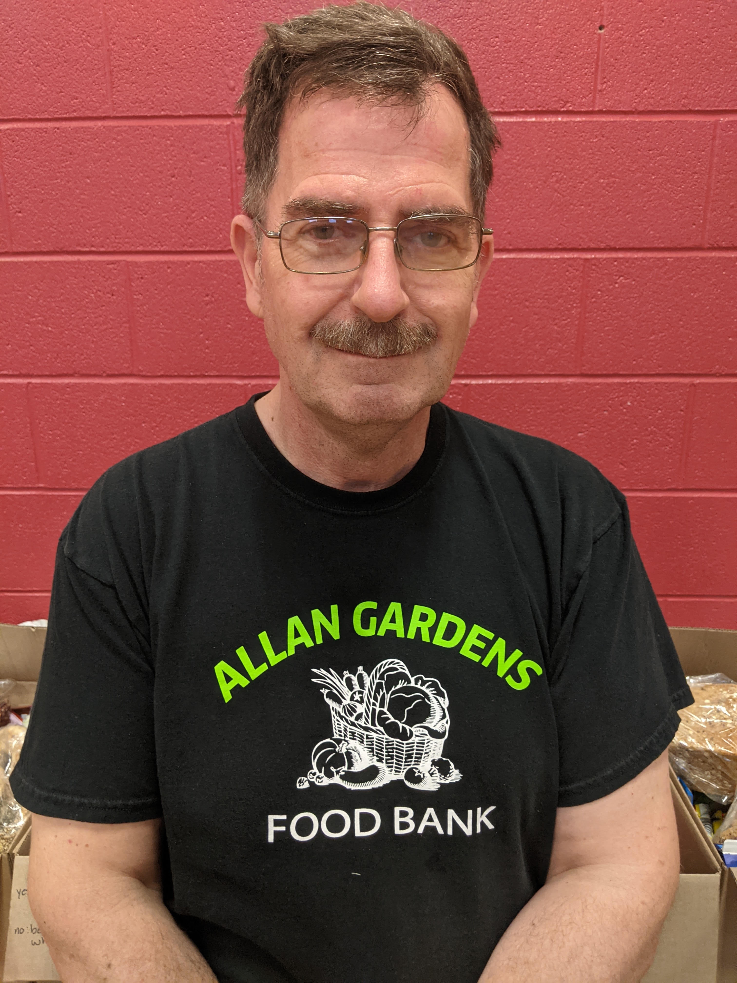 Head-and-shoulders portrait of Morgan Harris, short brown hair and a moustache, wearing glasses and a black t-shirt.