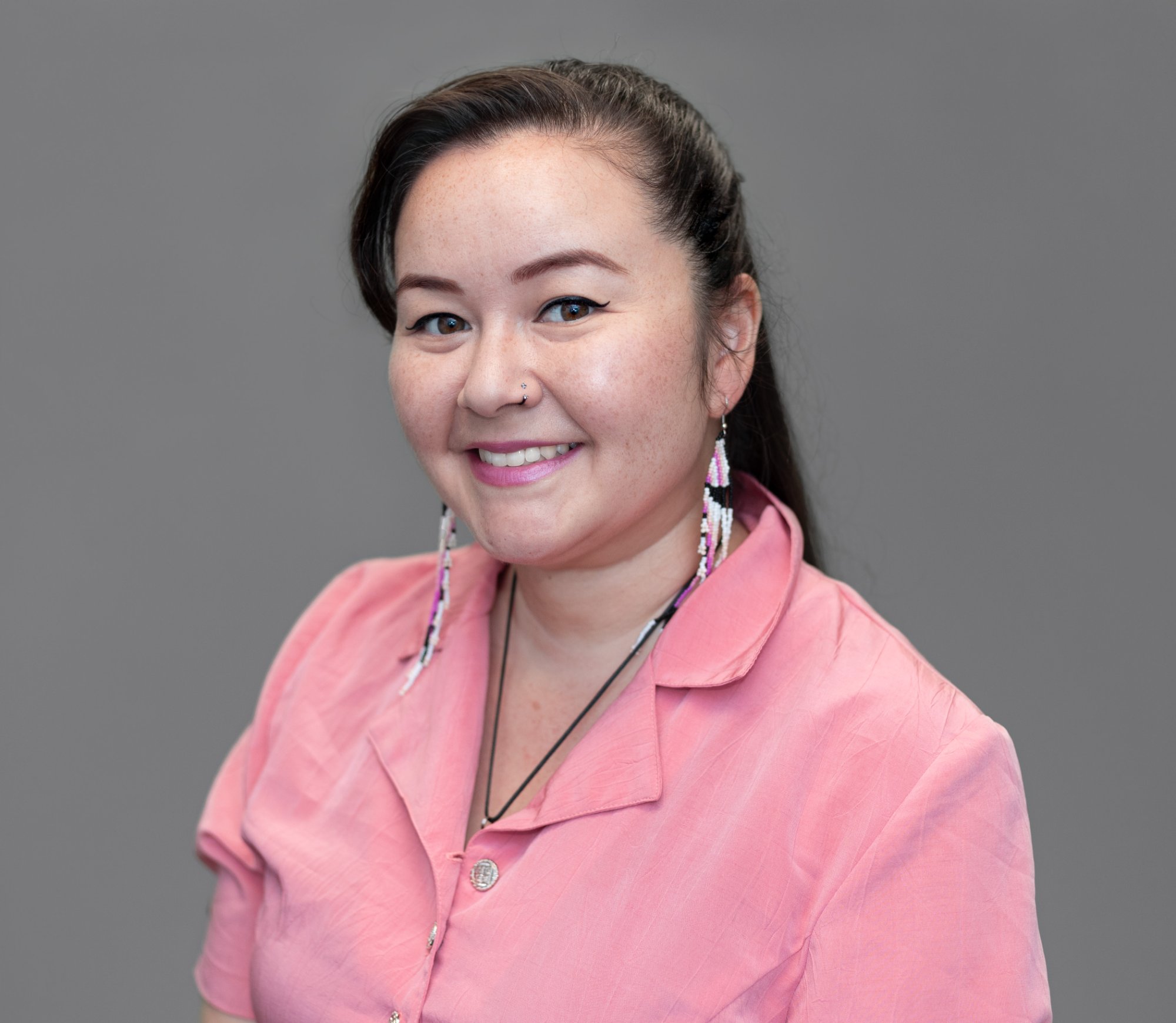 Head-and-shoulders portrait of Victoria Davis, long dark hair, wearing a pink collared top.