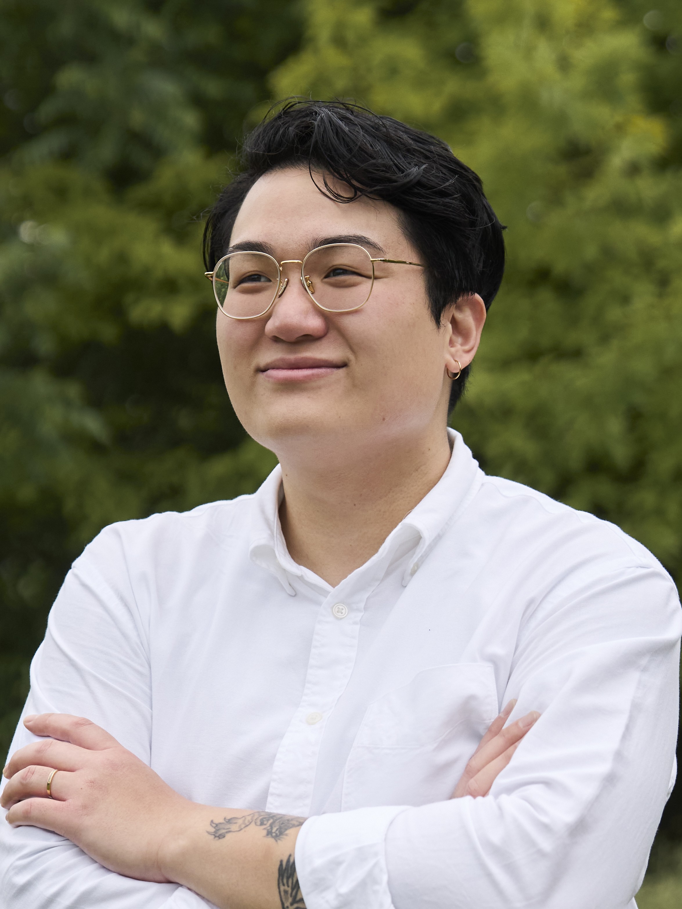 Head-and-shoulders portrait of Andi Hoàng-Lefranc, short dark hair, wearing glasses and a white shirt.