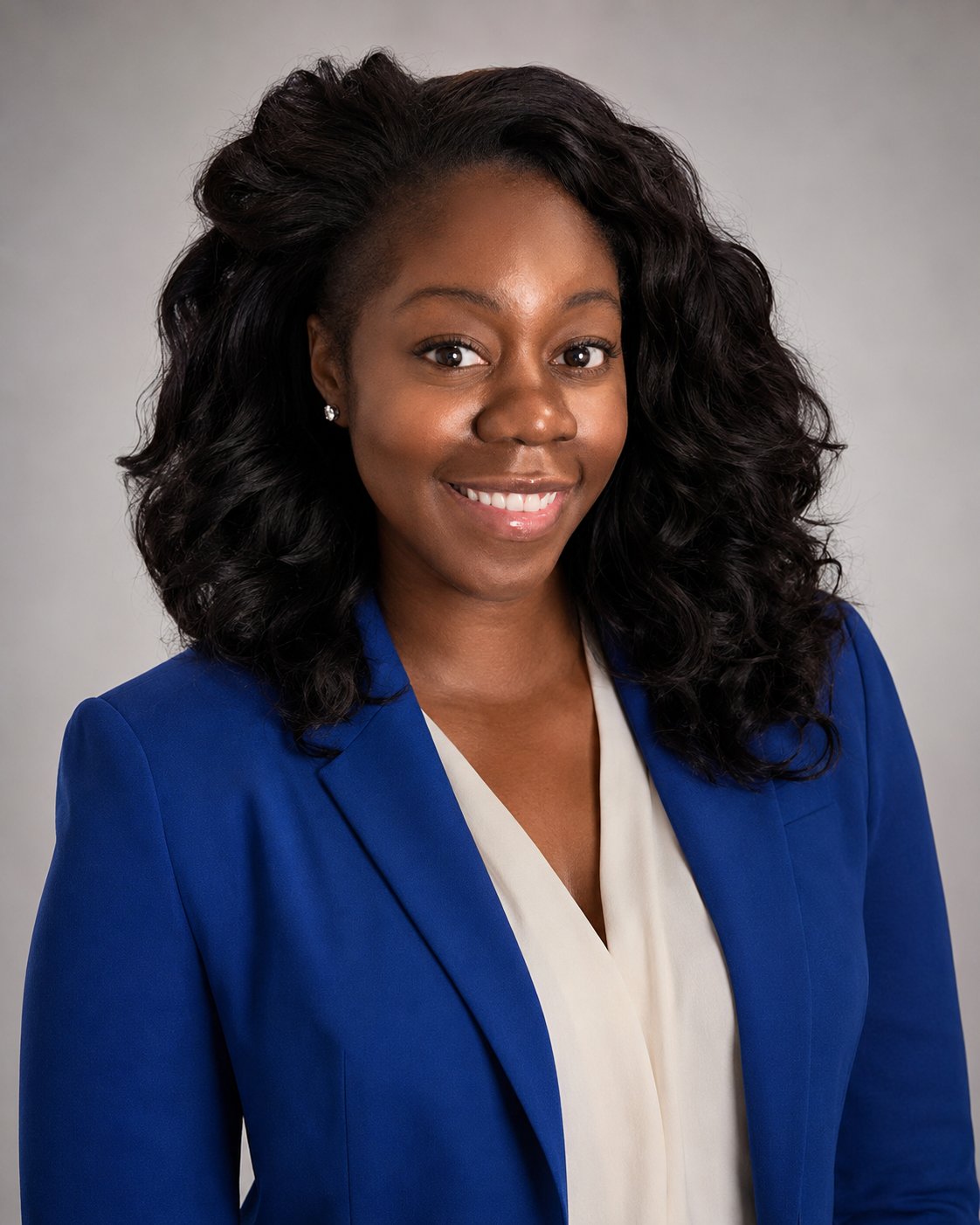 Head-and-shoulders portrait of Denise Walcott, shoulder-length curly dark hair, wearing a blue blazer and cream top.