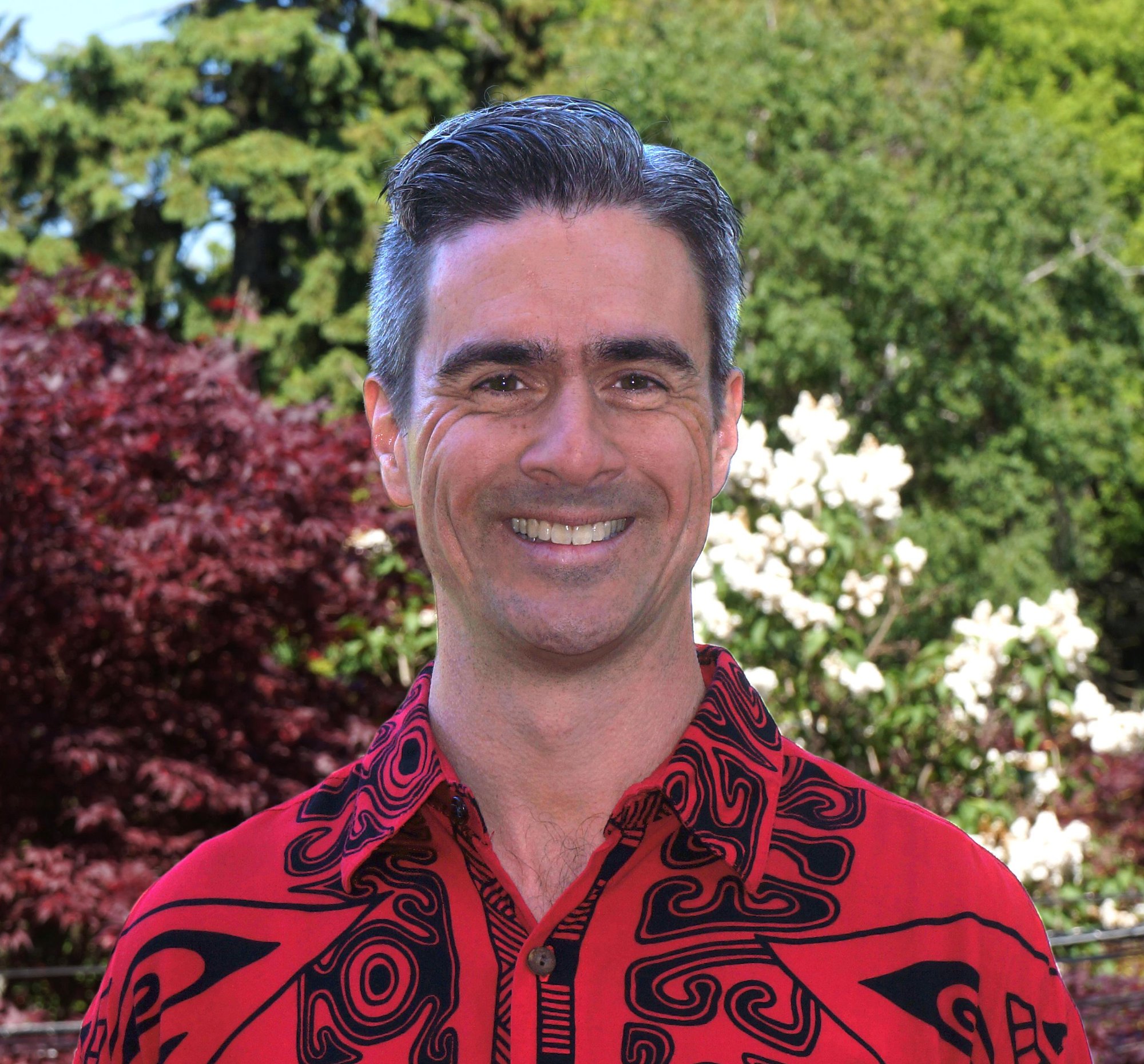 Head-and-shoulders portrait of Adam Smith, short grey hair, wearing a red and black patterned shirt.