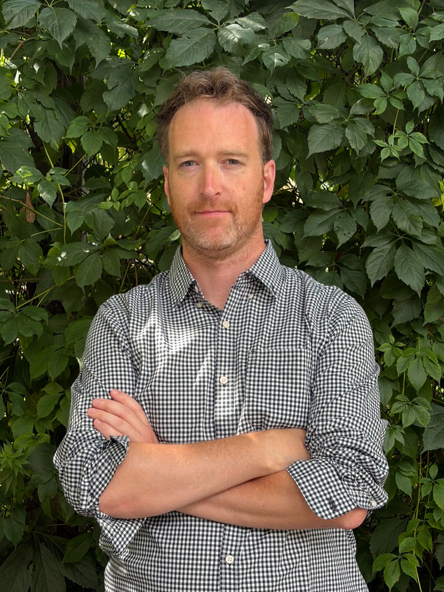 Head-and-shoulders portrait of George Fawcett, short brown hair and a beard, wearing a black and white checked shirt.