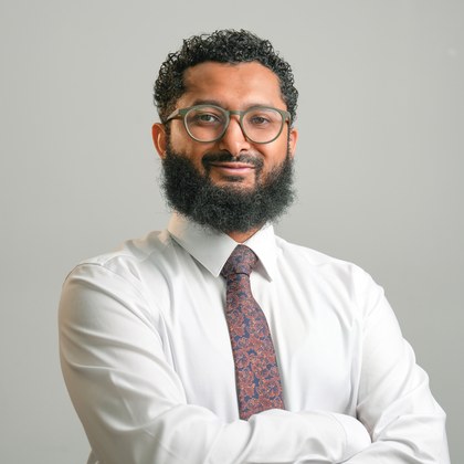 Head-and-shoulders portrait of Shaffni Nalir, curly dark hair and a beard, wearing a white shirt and glasses.